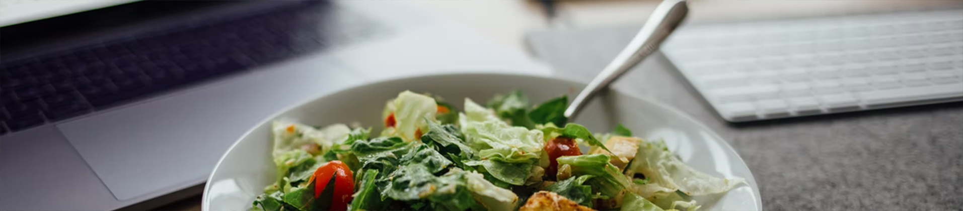 Salad in bowl near laptop and keyboard